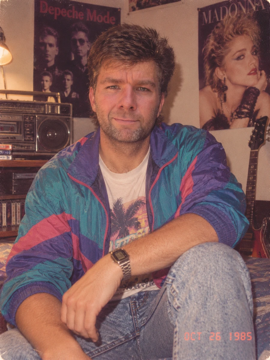 KI-inszeniertes Retro-Porträt von André Wunsch in einer bunten Jacke vor Musikpostern